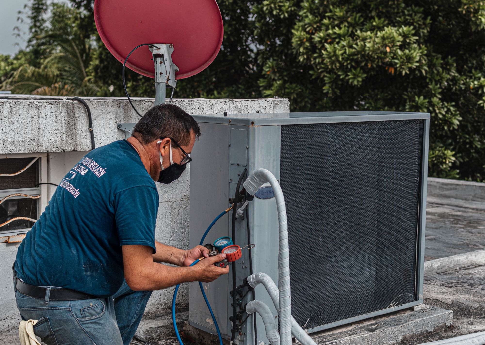 HVAC technician checking refrigerant gauges beside an outdoor air conditioning unit